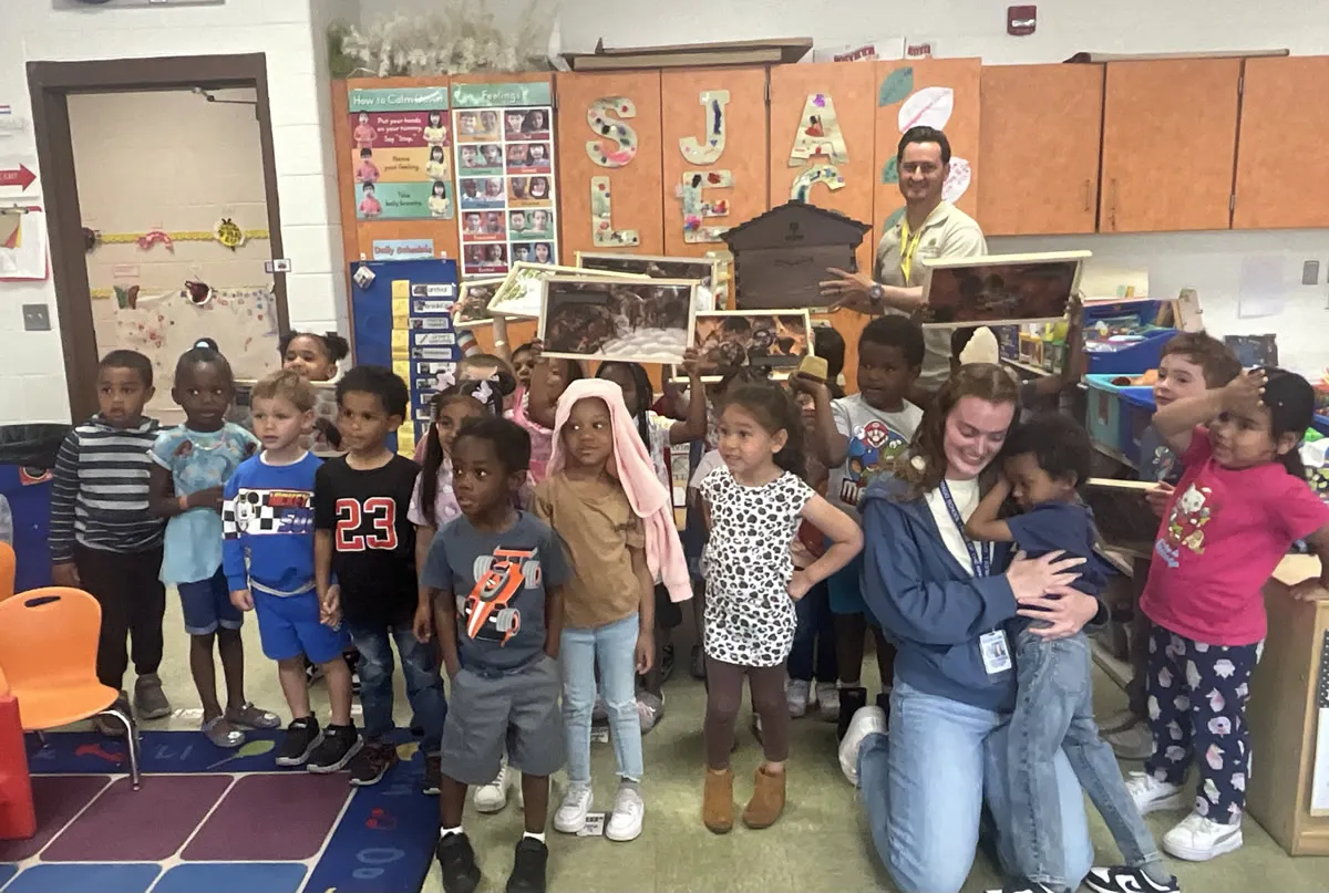 A classroom of students posing with hive frames after a pollinator lesson