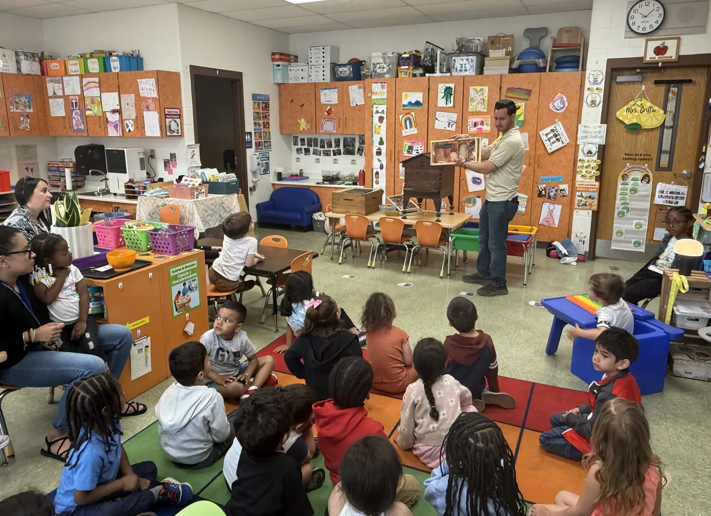 Students seated on the classroom floor watching a pollinator presentation