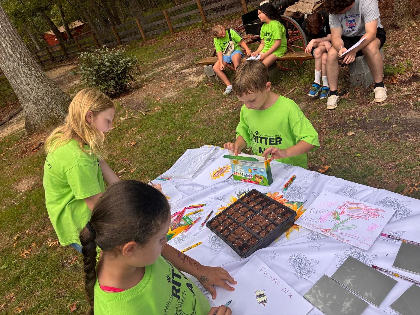 Campers at a table with seed trays and printed native plant handouts