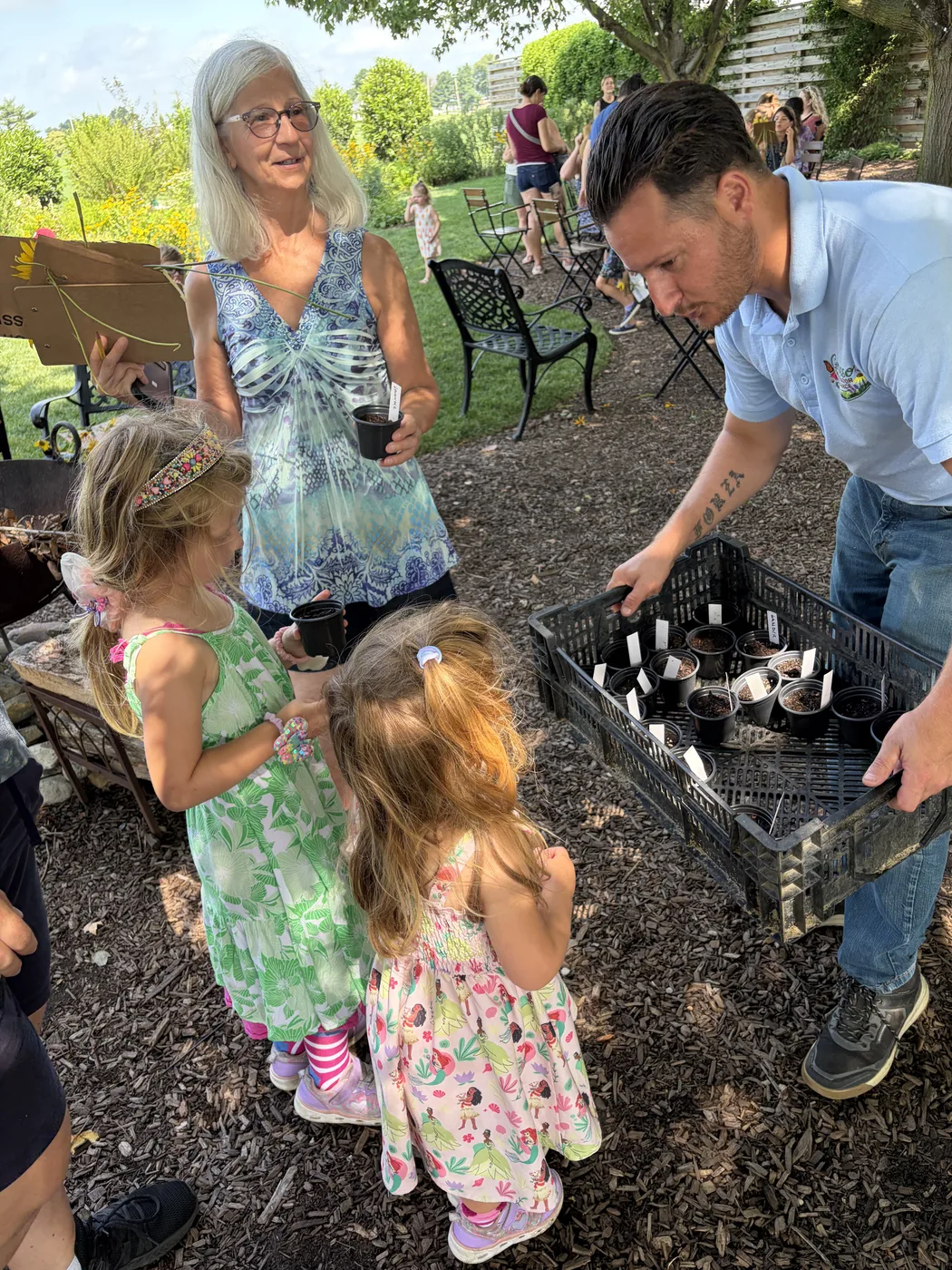 Two children helping founder Don Grasso sort a tray of young native plants