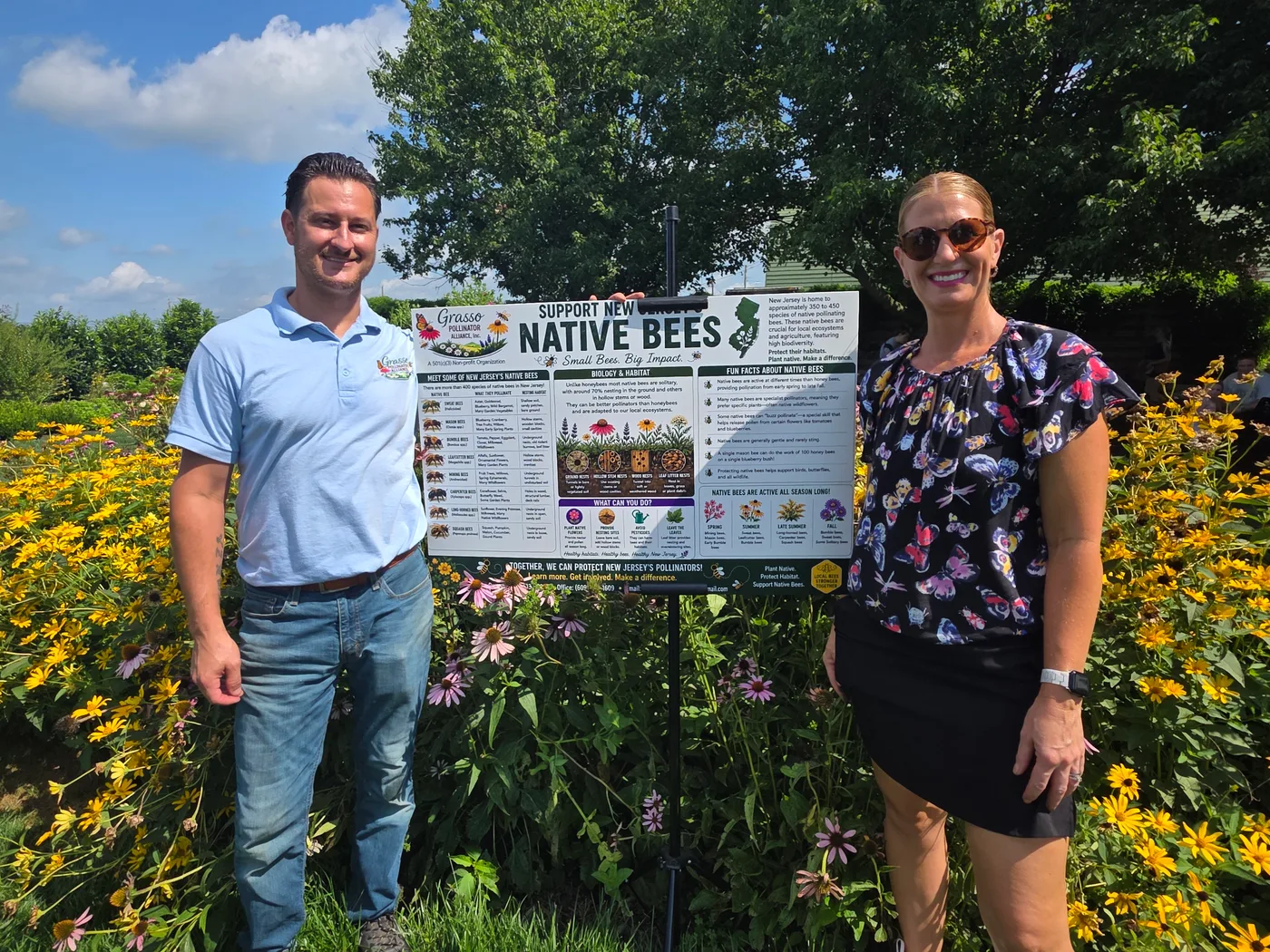 Founder Don Grasso with a guest beside the native bees banner in the garden