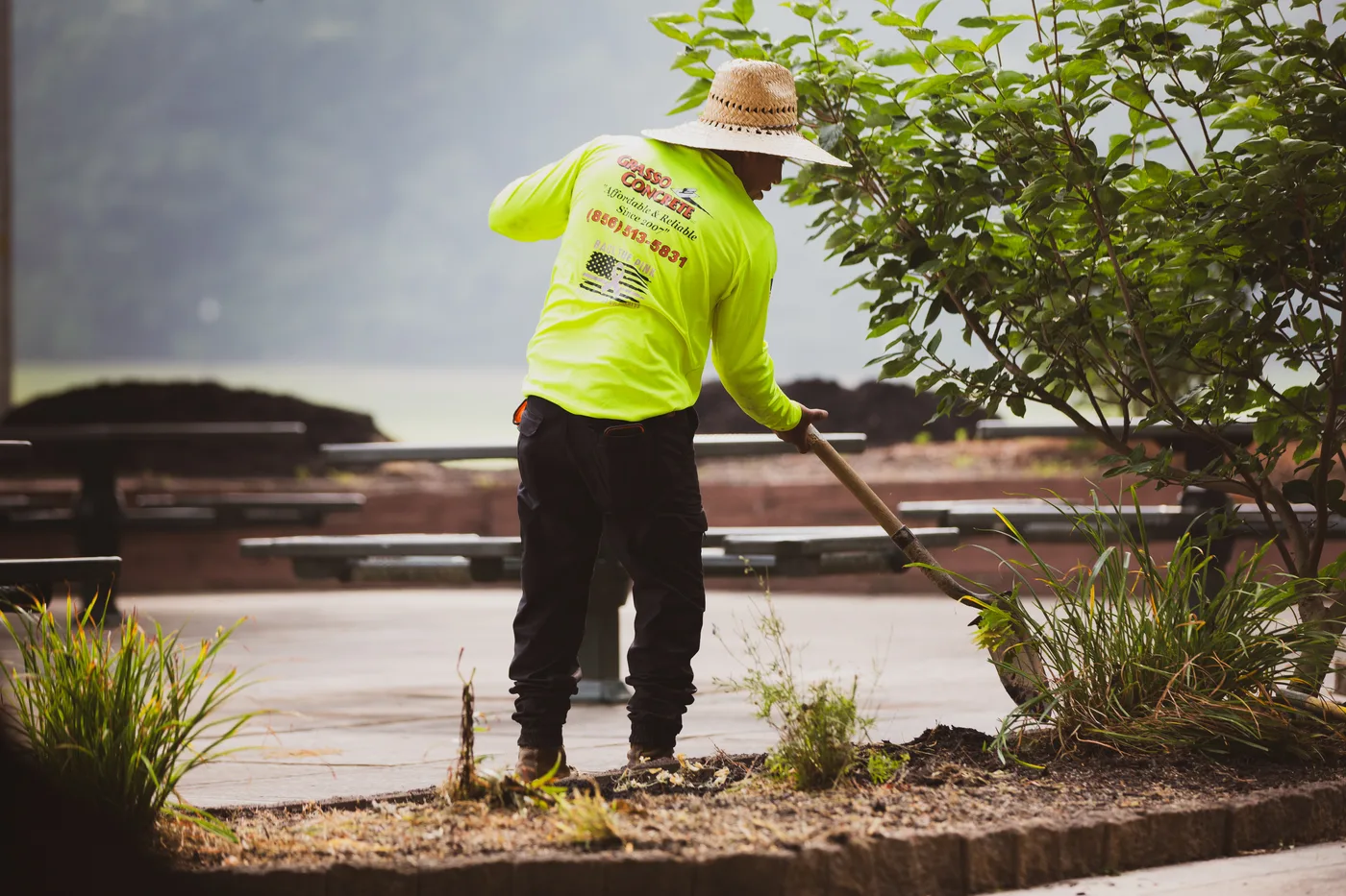 A volunteer in a hi-vis shirt raking soil level across a new bed